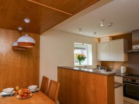 A kitchen and dining area with wooden furniture and white cabinets at Apartment 2 in Scarborough