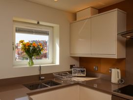 A kitchen corner with a sink a faucet yellow flowers in a vase a toaster and a kettle on the counter at Apartment 2 in Scarborough