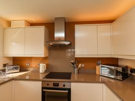 A kitchen with white cabinets a toaster kettle microwave oven and cooking utensils at Apartment 2 in Scarborough