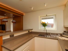 A kitchen with a sink a vase of flowers on the window sill a toaster and a dish rack at Apartment 2 in Scarborough