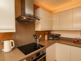 A kitchen with white cabinets a stovetop an oven a microwave a kettle and kitchen utensils at Apartment 2 in Scarborough