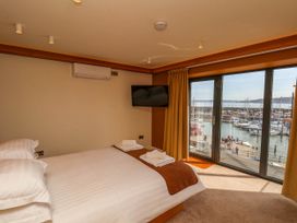 A bedroom with a double bed a wall-mounted television and large windows overlooking a marina at Apartment 2 in Scarborough