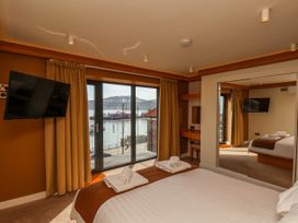 A bedroom with a bed facing a window overlooking water with hills in the background at Apartment 2 in Scarborough