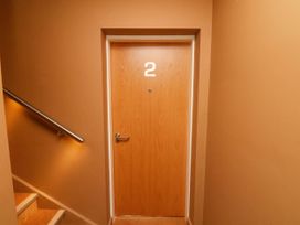 A wooden door with the number 2 next to a stairway with a handrail at Apartment 2 in Scarborough