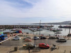 A view of a harbor with boats docked near the shore and cars parked along the street at Apartment 2 in Scarborough