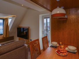 A dining table with bowls and croissants and a living area with a mounted television at Apartment 3 in Scarborough