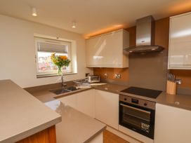 A kitchen with beige countertops white cabinets a window with flowers a stove an oven a toaster and a knife block at Apartment 3 in Scarborough