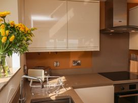 A kitchen countertop with a sink a drying rack a toaster a knife block and flowers on the windowsill at Apartment 3 in Scarborough