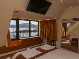 A bedroom with a bed and towel sets near a window with a view of a harbor at Apartment 3 in Scarborough