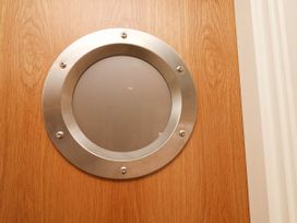 A wooden door with a round metal porthole window at Apartment 3 in Scarborough