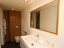 A bathroom with a sink and faucet a large mirror wall-mounted toilet and towels at Apartment 3 in Scarborough