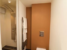 A bathroom with a walk-in shower towel rack with towels and a brown painted wall at Apartment 3 in Scarborough