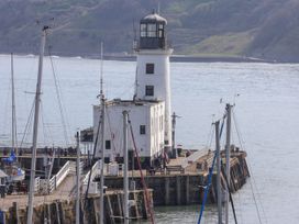 A lighthouse on a pier with boats docked and people walking near the water