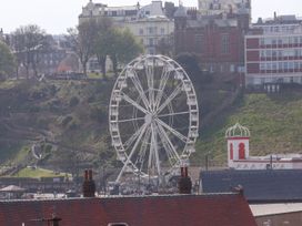 A large white Ferris wheel in front of a grassy hill with stairs and trees with buildings in the background at Apartment 3 Scarborough