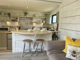 A kitchen with a bar area and stools at The Cow Shed in Mawgan Porth