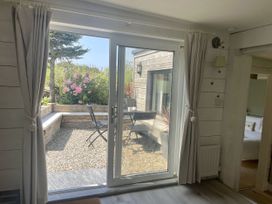 A living room with a view of the garden at The Cow Shed in Mawgan Porth