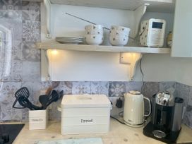 A kitchen with shelving, bowls, utensils, a kettle and a coffee machine at The Cow Shed in Mawgan Porth
