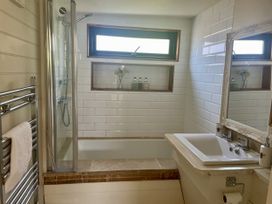 A bathroom with a shower, bathtub, sink and mirror at The Cow Shed in Mawgan Porth