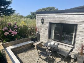An outdoor seating area with a table and chairs at The Cow Shed in Mawgan Porth