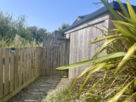 A gated entrance with a gravel path and plants at The Cow Shed in Mawgan Porth