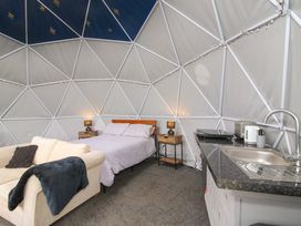 A dome-shaped room with a bed two bedside tables a sofa and a kitchenette at Meadow View - Bryn-Mawr Retreat in Brynmawr near Llanymynech