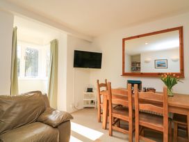 A dining area with a wooden table and chairs a wall-mounted television and a leather armchair at Millers Loft in Modbury