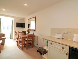 A dining area with wooden table and chairs next to a kitchen counter with toaster in a living room at Millers Loft in Modbury