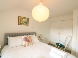 A bedroom with a bed white linens floral pillow a white rocking chair and a closet at Millers Loft in Modbury
