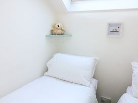 A bedroom with a white pillow and bed linens a stuffed animal on a small wall shelf and a framed picture on the wall at Millers Loft in Modbury