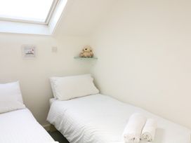 Two single beds with white linens and rolled towels on one bed in a bedroom at Millers Loft in Modbury