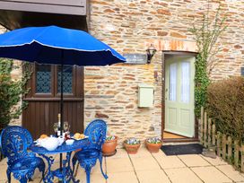 A patio with a blue metal table and chairs under a blue umbrella outside a stone building at Millers Loft in Modbury
