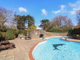 An outdoor swimming pool with dolphin design and stone wall with picnic tables at Millers Loft in Modbury
