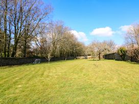 A large grassy garden with small trees a football goal and a stone wall at Millers Loft in Modbury