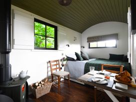 A small room with a bed a wood stove and a table with croissants at Bugail Hut in Llantwit Major