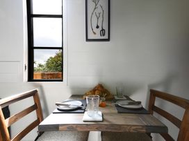 A dining table set with plates knives glasses and croissants near a window at Bugail Hut in Llantwit Major