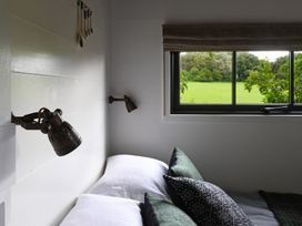 A bed with pillows beside a window showing a green field at Bugail Hut in Llantwit Major