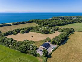 An aerial view of a building surrounded by fields trees and the sea in the background at Bugail Hut in Llantwit Major