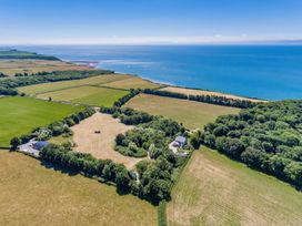 A coastal landscape with fields woods and a few buildings near the sea at Bugail Hut in Llantwit Major