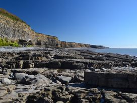 A rocky coastline with cliffs on the left and sea on the right at Bugail Hut in Llantwit Major