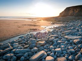 A rocky shoreline with large stones and a cliff at sunset at Bugail Hut in Llantwit Major