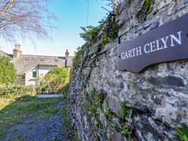 A pathway leading to a house with a stone wall and a sign at Garth Celyn in Porthmadog