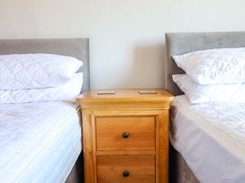 A bedroom with two beds and a bedside table at Garth Celyn in Porthmadog