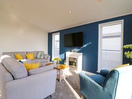 A living room with blue and gray sofas a coffee table and a wall-mounted TV at Number 43 The Poplars in Burnham Market