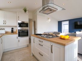 A kitchen with white cabinets wooden countertops a gas stove and a bowl of lemons at Number 43 The Poplars in Burnham Market