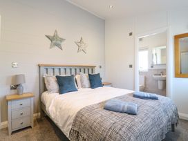 A bedroom with a double bed bedside tables and a doorway leading to a bathroom at Number 43 The Poplars in Burnham Market