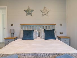 A bedroom with a bed with blue and patterned pillows and two star decorations on the wall at Number 43 The Poplars in Burnham Market