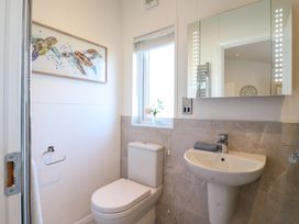 A bathroom with a toilet sink mirror window and a turtle picture at Number 43 The Poplars in Burnham Market