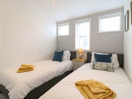 A bedroom with two single beds each with white bedding and blue pillows and a nightstand with a lamp between them at Number 43 The Poplars in Burnham Market