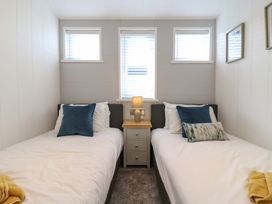 A bedroom with two single beds separated by a nightstand with a lamp at Number 43 The Poplars in Burnham Market