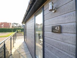 Exterior corridor with stone floor and glass railing at Number 43 The Poplars in Burnham Market